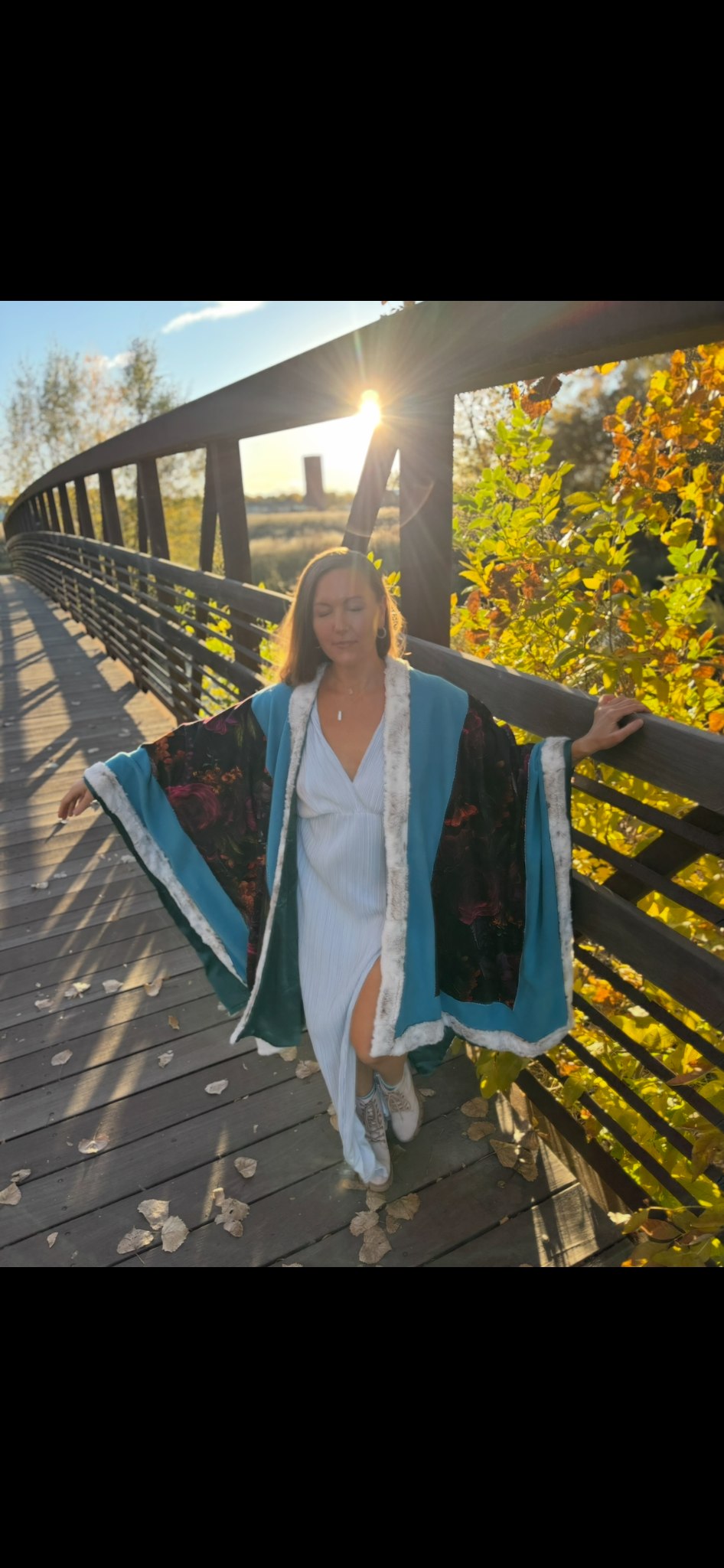 Megan in teal cloak on a sunlit bridge